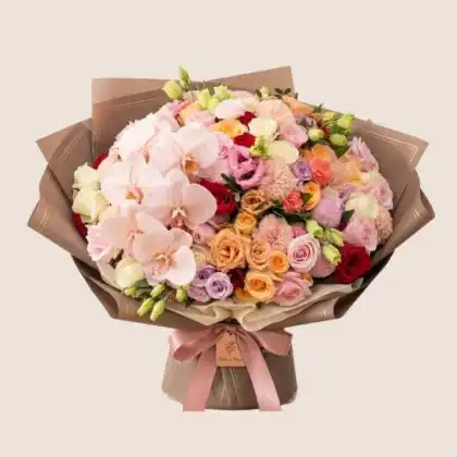 Handcrafted orchid and rose bouquet featuring vibrant blooms and lush greenery in a professional studio setting.