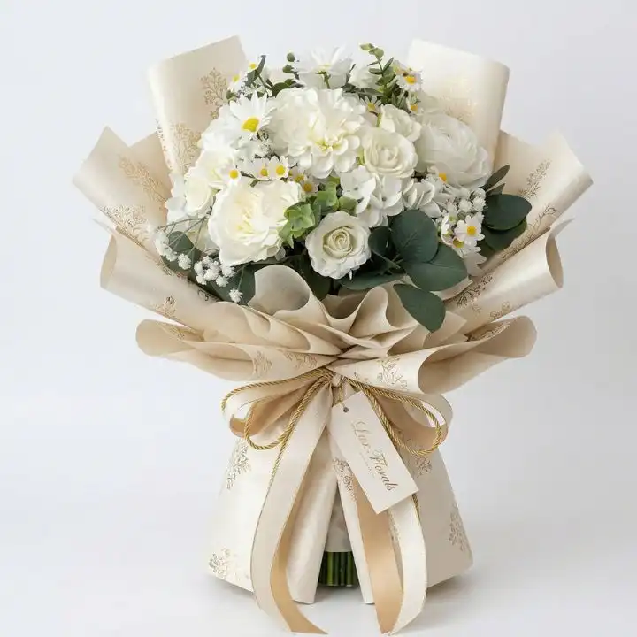 A stunning white rose and daisy bouquet elegantly arranged in a cream luxury textured paper wrap with a gold ribbon.