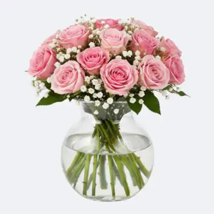 A lush arrangement of fresh pink roses in a vase with white baby's breath accents and green leaves.