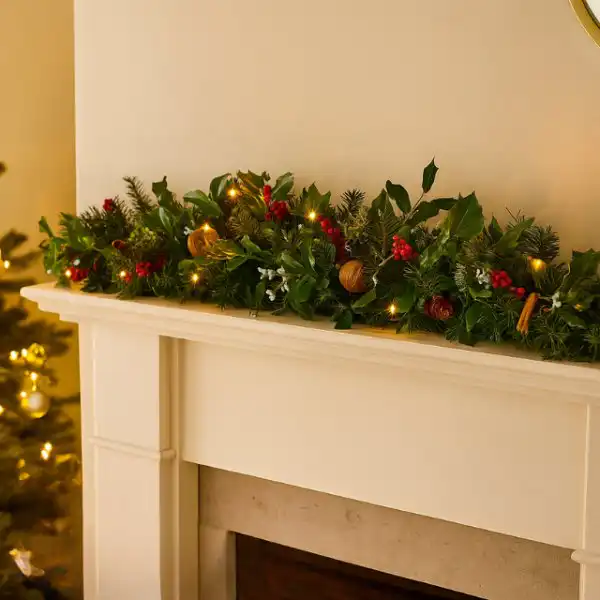 Christmas garland with lights for fireplace 1 A festive and realistic Christmas garland with lights for fireplace decor, featuring holly, berries, pine, and walnuts.