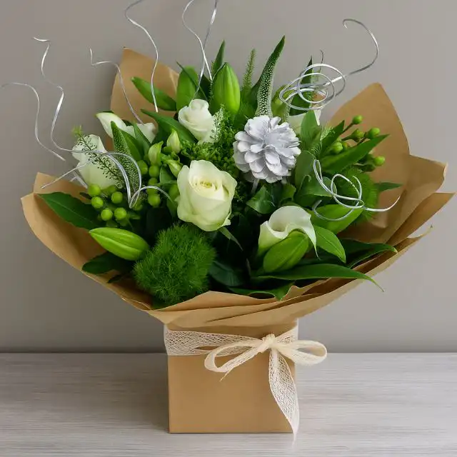 Christmas bouquet delivery 1 Hand-tied Christmas rose and lily bouquet with white flowers, green foliage, silver accents, and a pinecone in a brown kraft gift box. Christmas bouquet delivery