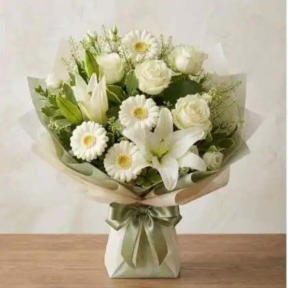 A serene White Sympathy Bouquet featuring fresh lilies, roses, and daisies arranged in a classic floral style.