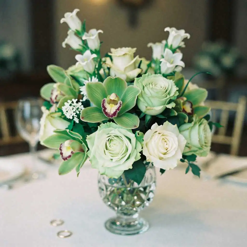 Blog 61 Green roses and orchids in crystal vase for 55th wedding anniversary celebration with couple celebrating in background